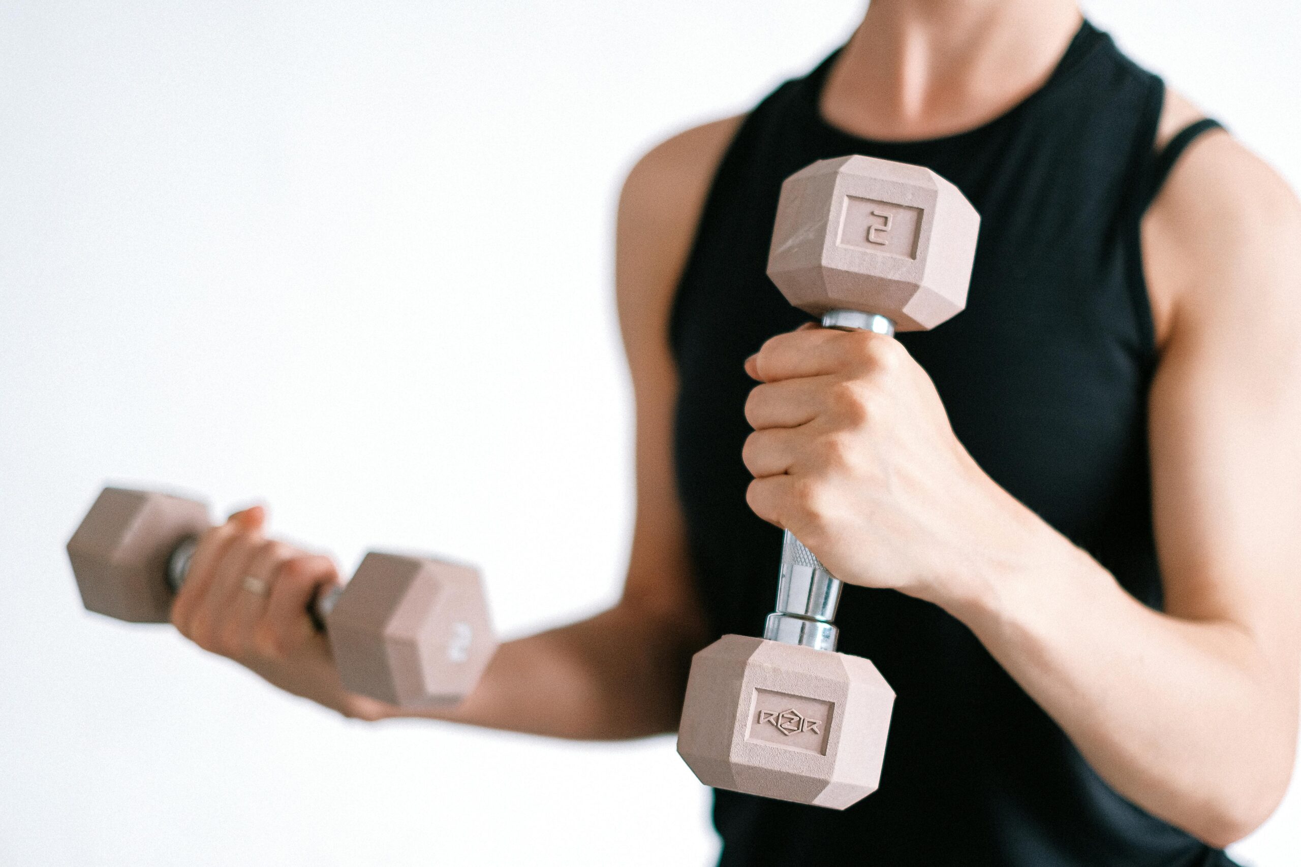 Close-up of a woman lifting dumbbells, focusing on a healthy lifestyle and fitness.